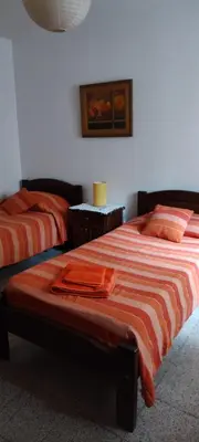 a bedroom with two beds with orange sheets at DEPARTAMENTO CORDOBA Capital ZONA NORTE in Cordoba