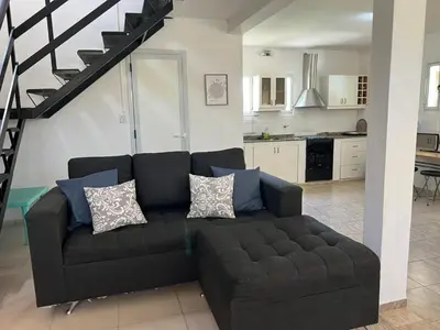 a living room with a black couch and a kitchen at MIRADOR Rest House in Bialet Massé