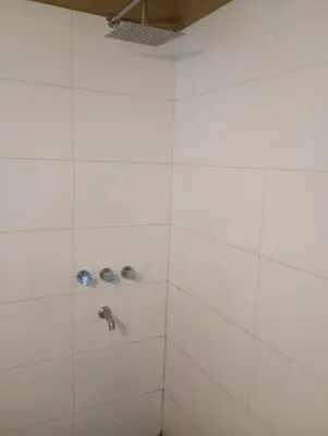 a white tiled shower with a silver faucet at Moderno PH, céntrico y económico, muy comodo, cocina, wifi, cochera techada privada in Cordoba