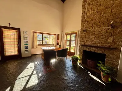a living room with a table and a stone fireplace at Posada del Valle solo adultos in Merlo