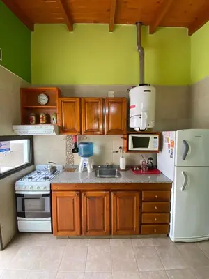a kitchen with wooden cabinets and a white refrigerator at Tica Masu in Villa Carlos Paz