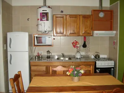a kitchen with a table and a white refrigerator at Tica Masu in Villa Carlos Paz