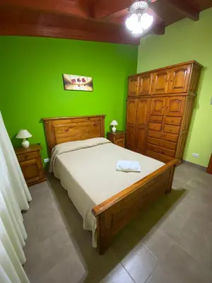 a bedroom with a large bed with a green wall at Tica Masu in Villa Carlos Paz