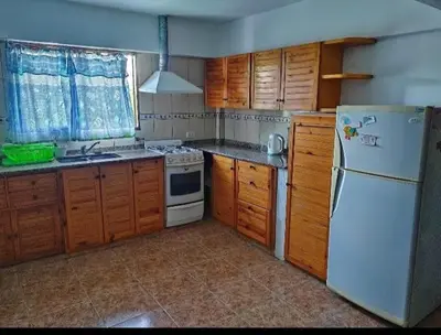 a kitchen with a white refrigerator and wooden cabinets at Lomas De Piquillin in Villa Carlos Paz