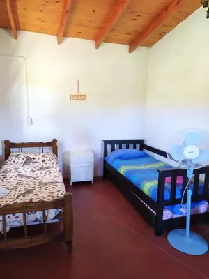 a bedroom with two beds and a table in it at Panaholma resort Cabañas de montaña in Panaholma