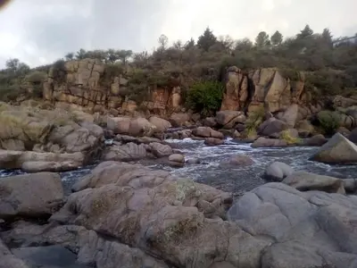 a river with rocks and a mountain in the background at Panaholma resort Cabañas de montaña in Panaholma