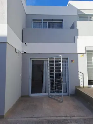 a white building with a door with a gate at La Paz 80 in Villa Carlos Paz