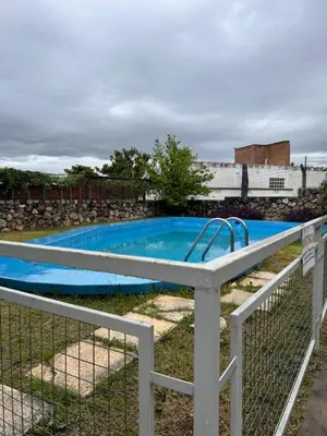 a blue swimming pool behind a fence at La Paz 80 in Villa Carlos Paz