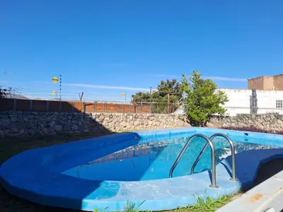 a blue swimming pool with a slide in a yard at La Paz 80 in Villa Carlos Paz