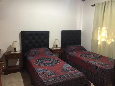 a bedroom with two beds and two tables with lamps at Cabañas MAHALO in Villa Rumipal