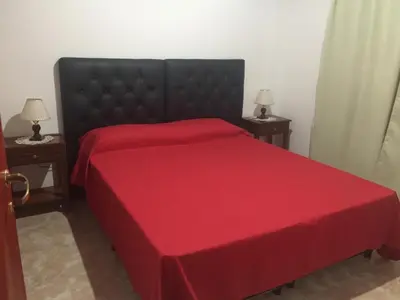 a bedroom with a red bed with two tables at Cabañas MAHALO in Villa Rumipal