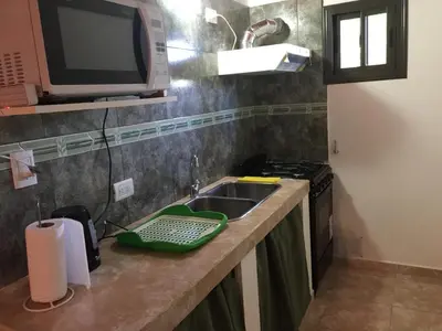a kitchen counter with a sink and a microwave at Cabañas MAHALO in Villa Rumipal