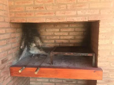a brick fireplace with a wooden bench in it at Cabañas MAHALO in Villa Rumipal