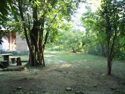 a park with a bench and trees next to a house at Cabañas de Colores in Los Reartes