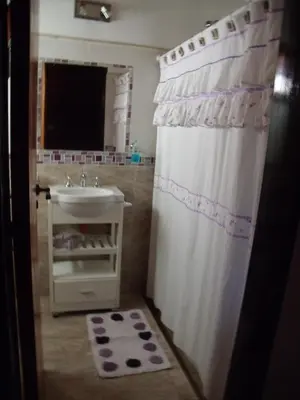a bathroom with a white shower curtain and a sink at Cabañas de Colores in Los Reartes