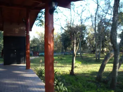 a wooden pavilion in a park with trees and grass at Cabañas de Colores in Los Reartes