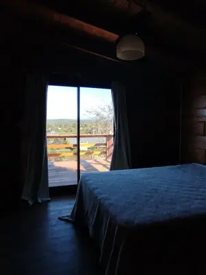 a bedroom with a bed and a large window at Cabaña de quebracho de dos pisos in Villa General Belgrano