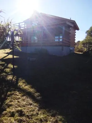 a house with the sun shining on the roof at Cabaña de quebracho de dos pisos in Villa General Belgrano