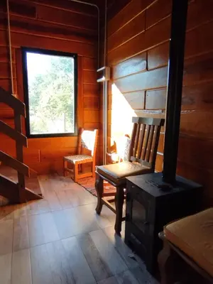 a room with a stove and a chair in a cabin at Cabaña de quebracho de dos pisos in Villa General Belgrano