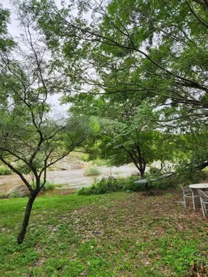 a picnic table and chairs next to a river at Altos de Grecia Cabaña 3 in Villa Carlos Paz