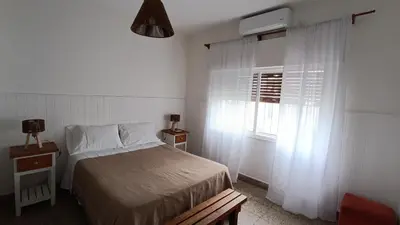 a bedroom with a bed and a window with white curtains at Departamento interno in Alta Gracia