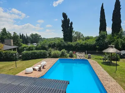 a large swimming pool in a yard with a garden at Departamento con pileta cerca del centro in Villa General Belgrano