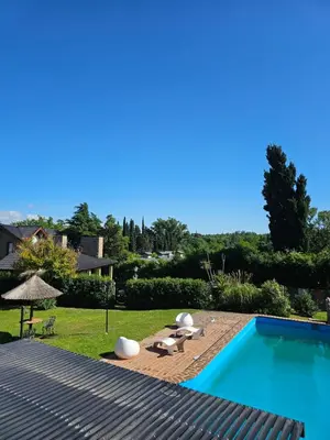a swimming pool with two loungers next to a yard at Departamento con pileta cerca del centro in Villa General Belgrano