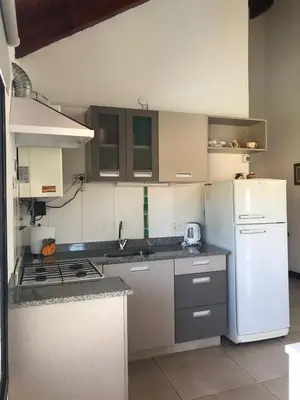 a kitchen with white appliances and a white refrigerator at Departamento con pileta cerca del centro in Villa General Belgrano