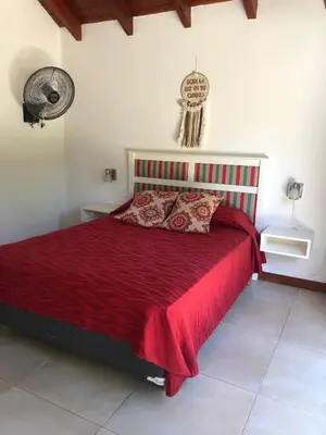 a bedroom with a bed with a red bedspread at Departamento con pileta cerca del centro in Villa General Belgrano