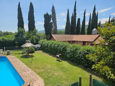 a garden with a swimming pool and a house at Departamento con pileta cerca del centro in Villa General Belgrano