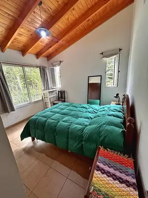 a bedroom with a green bed in a room with windows at Casa Longoseiros in Merlo