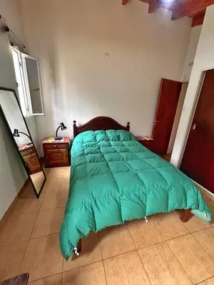 a bed with a green comforter in a bedroom at Casa Longoseiros in Merlo