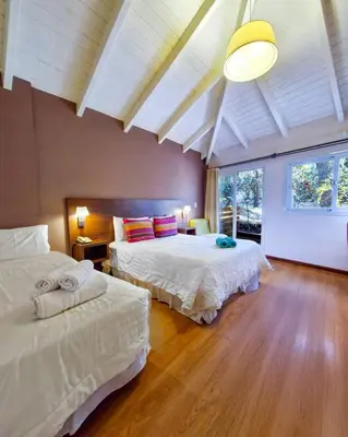 a bedroom with two beds and a large window at Berna Hotel & Spa in Villa General Belgrano