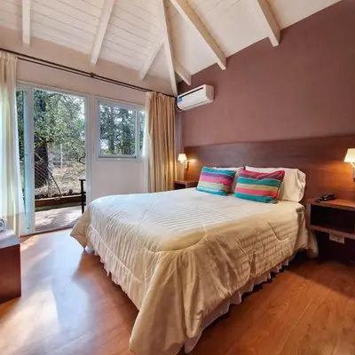 a bedroom with a large bed with two colorful pillows at Berna Hotel & Spa in Villa General Belgrano
