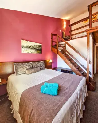 a bedroom with a large bed and a staircase at Berna Hotel & Spa in Villa General Belgrano