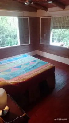 a large bed in a room with two windows at Posada del Arroyo in Las Rabonas