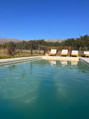 a pool of water with lounge chairs in the background at Ranchos de la Tata in Las Calles