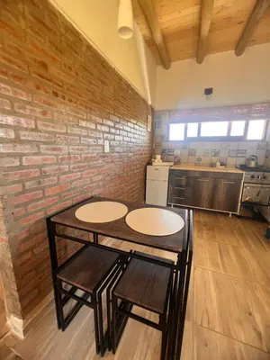 a kitchen with a table and chairs and a brick wall at Ranchos de la Tata in Las Calles