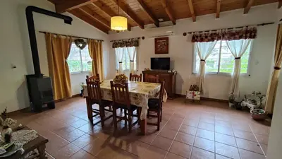 a dining room with a table and chairs and windows at Viento Sur in Villa General Belgrano
