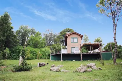 a house in a field with rocks in front of it at Viento Sur in Villa General Belgrano