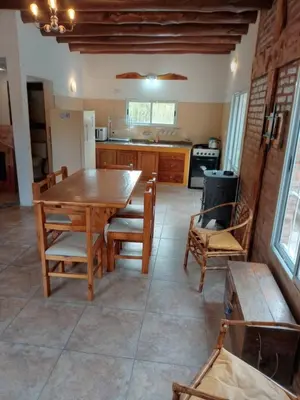 a kitchen with a wooden table and some chairs at CABAÑA PRIVADA NALÚ 2, Villa Ciudad Parque a 150m Río Los Reartes in Villa Ciudad Parque