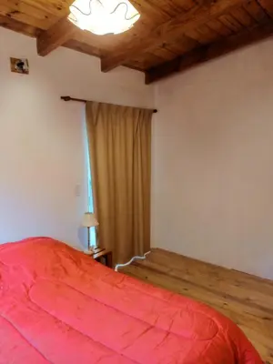a bedroom with a red bed and a window at CABAÑA PRIVADA NALÚ 2, Villa Ciudad Parque a 150m Río Los Reartes in Villa Ciudad Parque