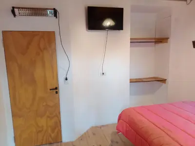 a room with a door and a tv on the wall at CABAÑA PRIVADA NALÚ 2, Villa Ciudad Parque a 150m Río Los Reartes in Villa Ciudad Parque