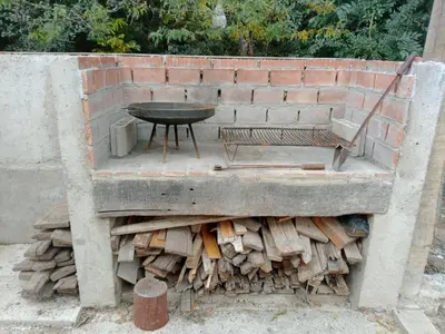 a grill with a bench and a pile of wood at CABAÑA PRIVADA NALÚ 2, Villa Ciudad Parque a 150m Río Los Reartes in Villa Ciudad Parque