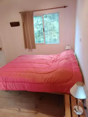 a bed with a red comforter in a room with a window at CABAÑA PRIVADA NALÚ 2, Villa Ciudad Parque a 150m Río Los Reartes in Villa Ciudad Parque