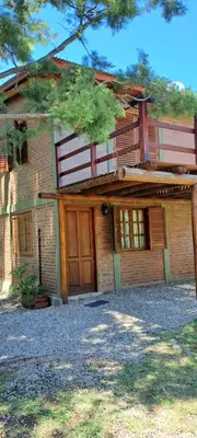 a large brick house with a wooden door at TIERRA SERRANA CABAÑAS s in Villa Anizacate