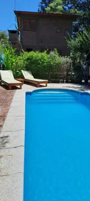 a large blue swimming pool next to a house at TIERRA SERRANA CABAÑAS s in Villa Anizacate