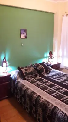 a bedroom with a bed with green walls and two lamps at Confortable Carlos Paz Céntrico 4 personas Estac Interno in Villa Carlos Paz