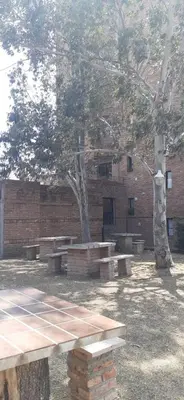 a brick building with picnic tables and a tree at Confortable Carlos Paz Céntrico 4 personas Estac Interno in Villa Carlos Paz