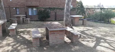 a group of benches sitting next to a tree at Confortable Carlos Paz Céntrico 4 personas Estac Interno in Villa Carlos Paz